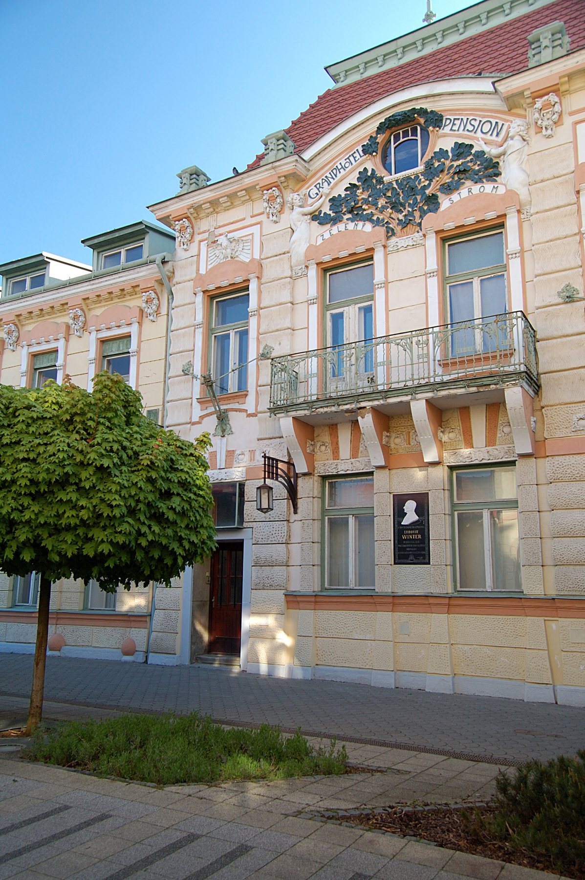 Zelený strom – priečelie s reliéfom stromu a nápisom Grand Hotel Pension